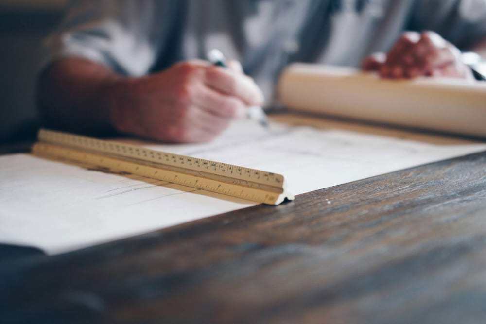 Man sitting at desk working on blueprints for a house